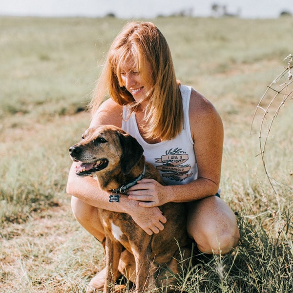 Dr. Linzi Newth cuddling her dog while sitting in a field